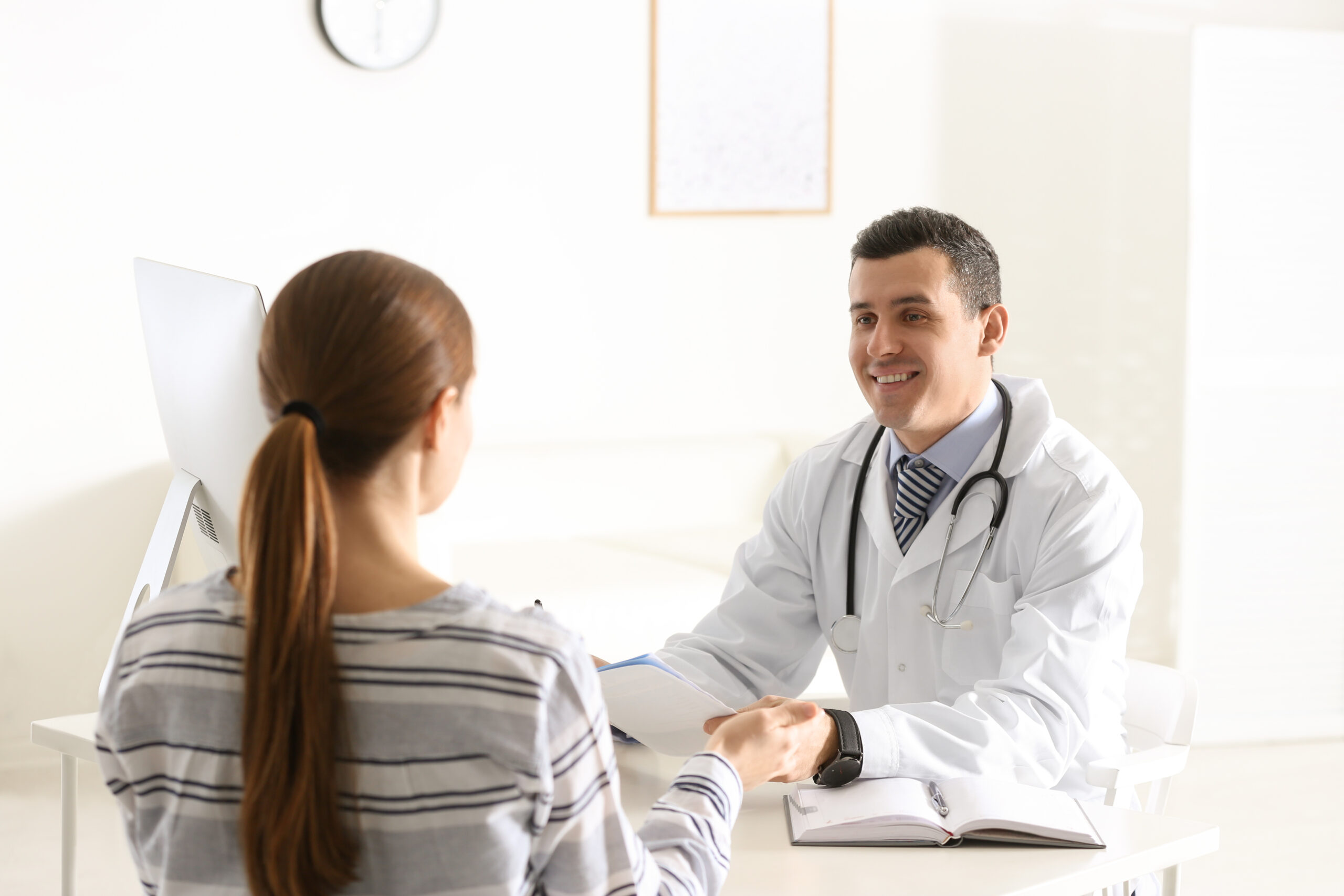 Doctor,Consulting,Patient,At,Desk,In,Clinic